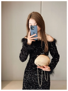 Detail of a spherical gold metal clutch bag with mirror finish and slim chain strap