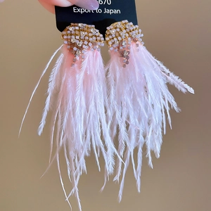 Close-up of sparkling rhinestone clusters and soft pink feather fringe earrings