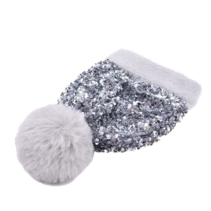 Detailed close-up of shiny sequins and a fluffy grey faux fur pompom on a knit winter beanie