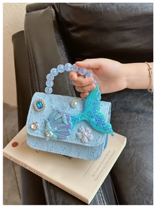 Dettaglio ricamo sirena con paillettes e manico di perle su borsa in pizzo blu