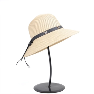 Close-up of straw sun hat featuring a black leather band with silver butterfly charms