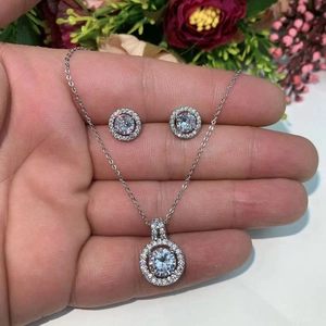 Detailed macro of the round halo zircon pendant and matching stud earrings on palm