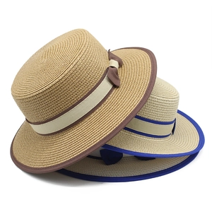 Close-up of two woven straw boater hats with decorative ribbons and bows on white background