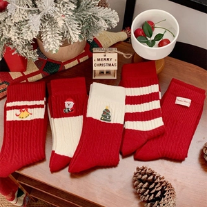 Pack de 2 chaussettes de Noël festives rouges et blanches brodées sur une table en bois