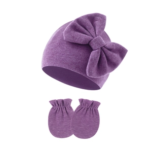 Detailed close-up of soft ribbed knit baby beanie with bow and ruffled matching mittens