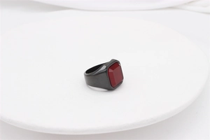 Detailed view of men's gunmetal stainless steel ring with a square red gemstone inlay
