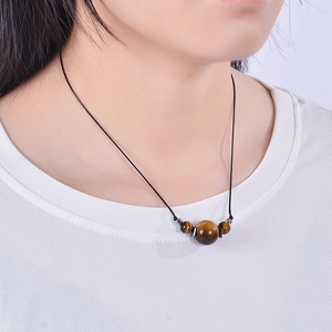 Tiger eye stone pendant necklace with adjustable black cord on a female model