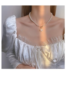 Detail of elegant pearl necklace with heart pendant and gold toggle clasp on neckline