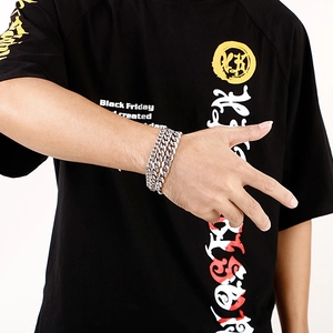 Mens thick silver stainless steel Cuban link chain bracelet worn on wrist over black tee