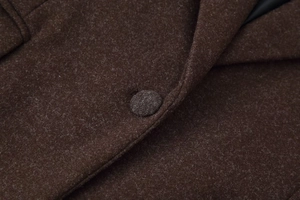 Close-up of the notched lapel and matching fabric-covered button on a wool coat