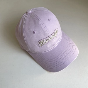 Detailed close-up of purple cotton baseball cap with Hiranga cursive letter embroidery