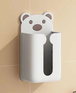 Close-up of wall-mounted bear tissue box in white and brown on beige tiled wall