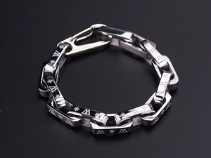 Detail of silver link bracelet with rectangular links featuring sun and letter engravings