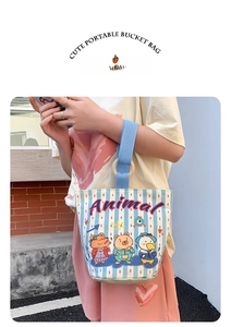 Detail of blue striped canvas bucket bag with cute animal prints held by a model