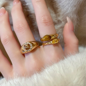 Detailed view of three gold-plated rings featuring amber tiger eye stones and zircons
