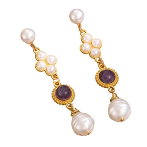 Close-up of vintage gold earrings with pearls and purple marble stone detail