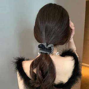 Elegant black organza scrunchie with glitter trim worn on a low ponytail hair style