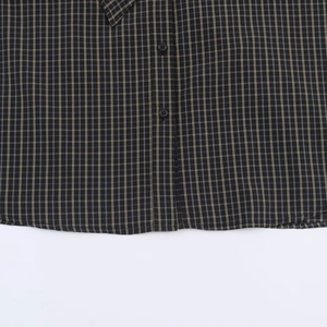 Close-up of black and brown plaid shirt featuring textile texture and round buttons