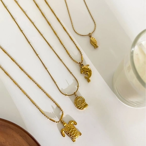Vintage titanium steel gold necklace set with sea turtle dolphin pendants on white steps