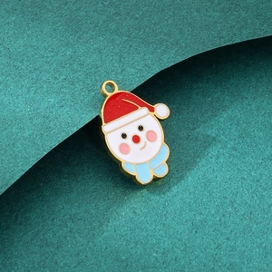 Macro d'un pendentif bonhomme de neige doré avec détails en émail sur fond vert foncé