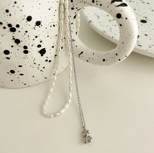 Detail of 925 silver bear pendant and pearl double layer necklace on ceramic art cup