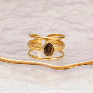 Detail of 18k gold multilayer stainless steel ring with a brown oval natural stone