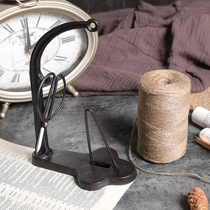 Vintage cast iron spool holder with scissors and jute twine on a rustic tabletop