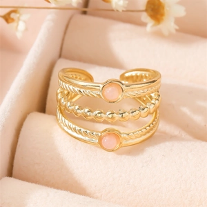 Detailed close-up of a triple-layered gold-plated ring with pink gems on velvet
