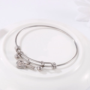 Silver guitar charm bangle with adjustable steel band and metal beads on ceramic plate