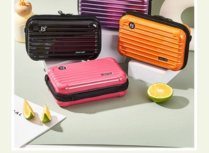 Mini hardshell cosmetic cases in multiple colors displayed on a green background