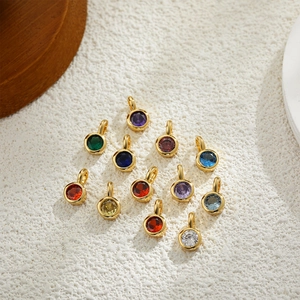 Macro shot of thirteen circular 18K gold birthstone charms in various vibrant colors