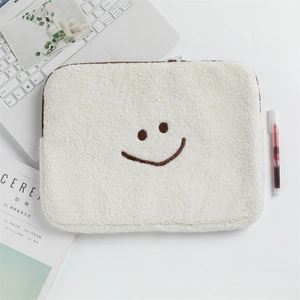 Vue détaillée de la housse d'ordinateur en polaire blanche avec smiley brodé et zip