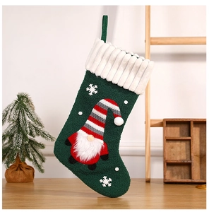 Detail of dark green plush Christmas stocking with Santa Claus embroidery on wooden table
