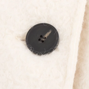 Elegant white wool coat detail showing a black four-hole button and premium fabric texture