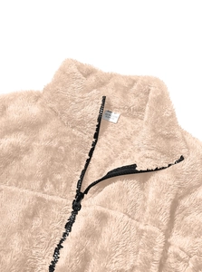 Detail of soft beige fleece jacket featuring a black half-zip collar and textile texture