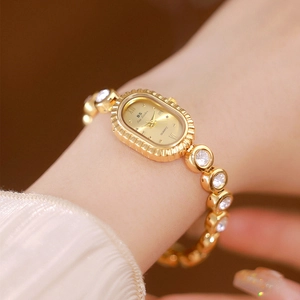 Close-up of elegant gold oval watch with crystal bezel and Roman numerals on woman wrist
