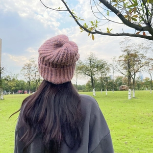 Detail view of pink chunky knit beanie with thick yarn texture on model in park setting