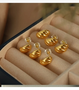 Macro shot of three pairs of golden spiral horn hoop earrings in a velvet jewelry box
