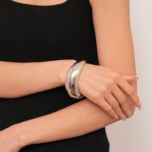 Detailed close-up of a wide polished silver cuff bracelet with abstract wavy geometry