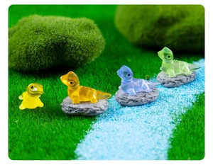 Luminous resin dinosaur miniatures in yellow, orange, blue and green on a mossy micro landscape