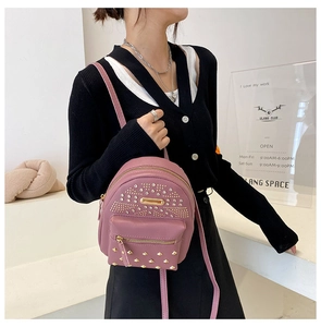 Detailed view of pink punk style backpack featuring gold studs and metal hardware accents