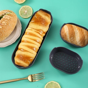 Detail of dark gray silicone bread molds with baked pastries on a teal background