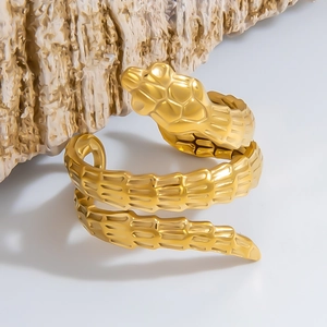 Macro detail of golden snake ring showing intricate scale texture on a wooden stand