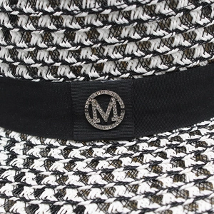 Detail of black and white woven straw hat with rhinestone M buckle on ribbon