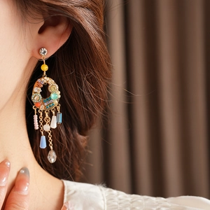 Détail de boucles d'oreilles à pompons colorés avec cristaux et métal doré sur un mannequin