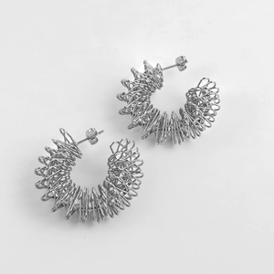 Detailed macro view of silver spiral coiled hoop earrings with minimalist spring design