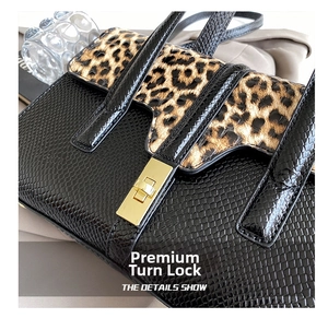 Macro shot of gold metal twist lock on a faux snake-textured leopard print handbag