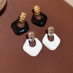 Detailed macro view of geometric diamond drop earrings with oil drip finish on leather