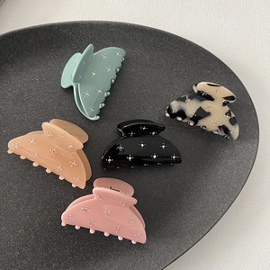 Sparkling pastel hair claws with rhinestone floral patterns on a dark display tray