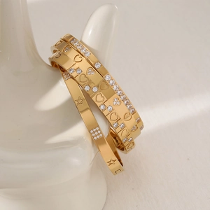 Polished gold stainless steel bangle set with heart and star zircon charms on hand model